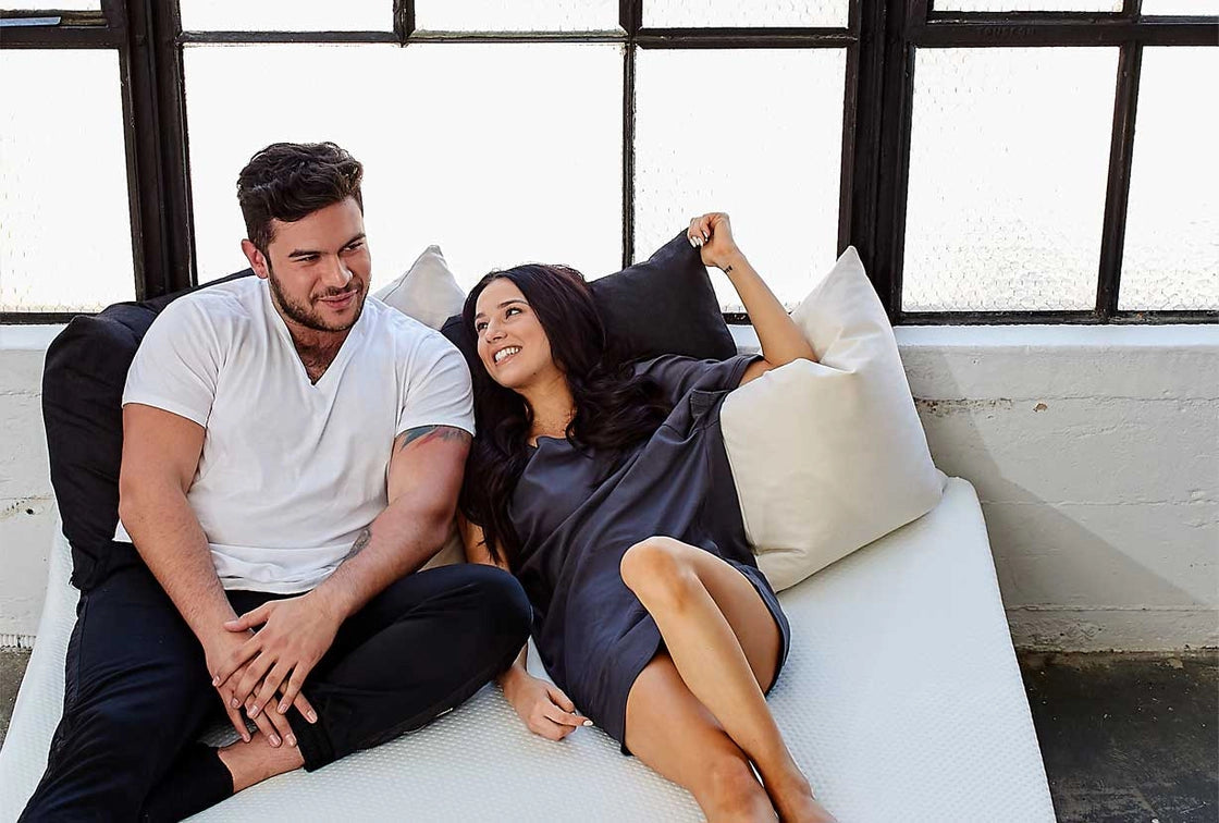 Couple sitting on a Luxi mattress, lifestyle product photo