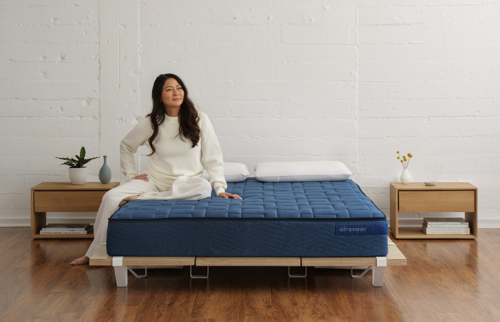 Woman sitting on an Airweave mattress in a bedroom, from the Airweave website