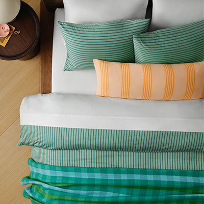 Overhead view of a made bed dressed in Brooklinen striped sheets and pillowcases, product photo from Brooklinen