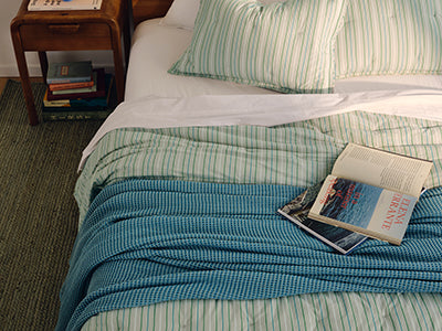 Brooklinen striped bed sheets and pillowcases styled with a waffle-weave throw blanket, product photo from Brooklinen