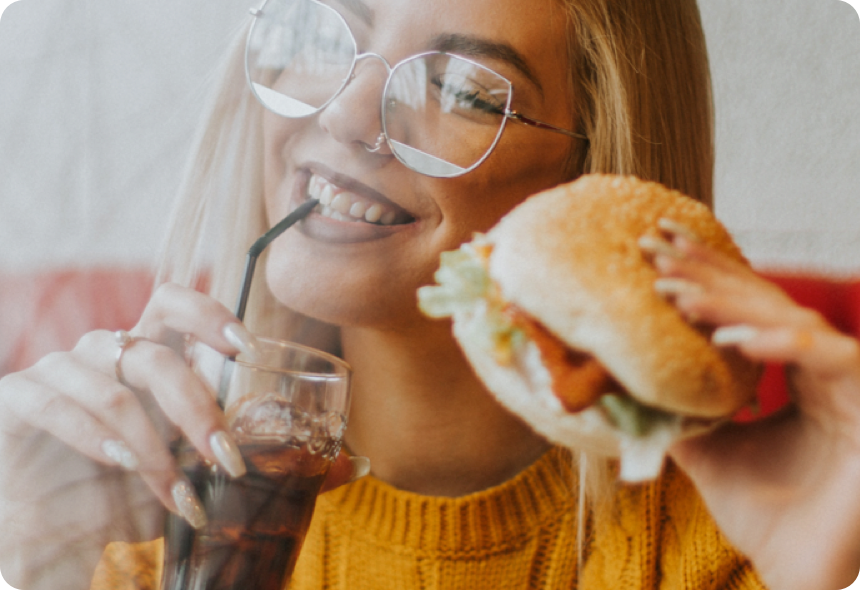 Person enjoying a drink and a burger, lifestyle photo from Drop's marketing site representing its dining rewards category