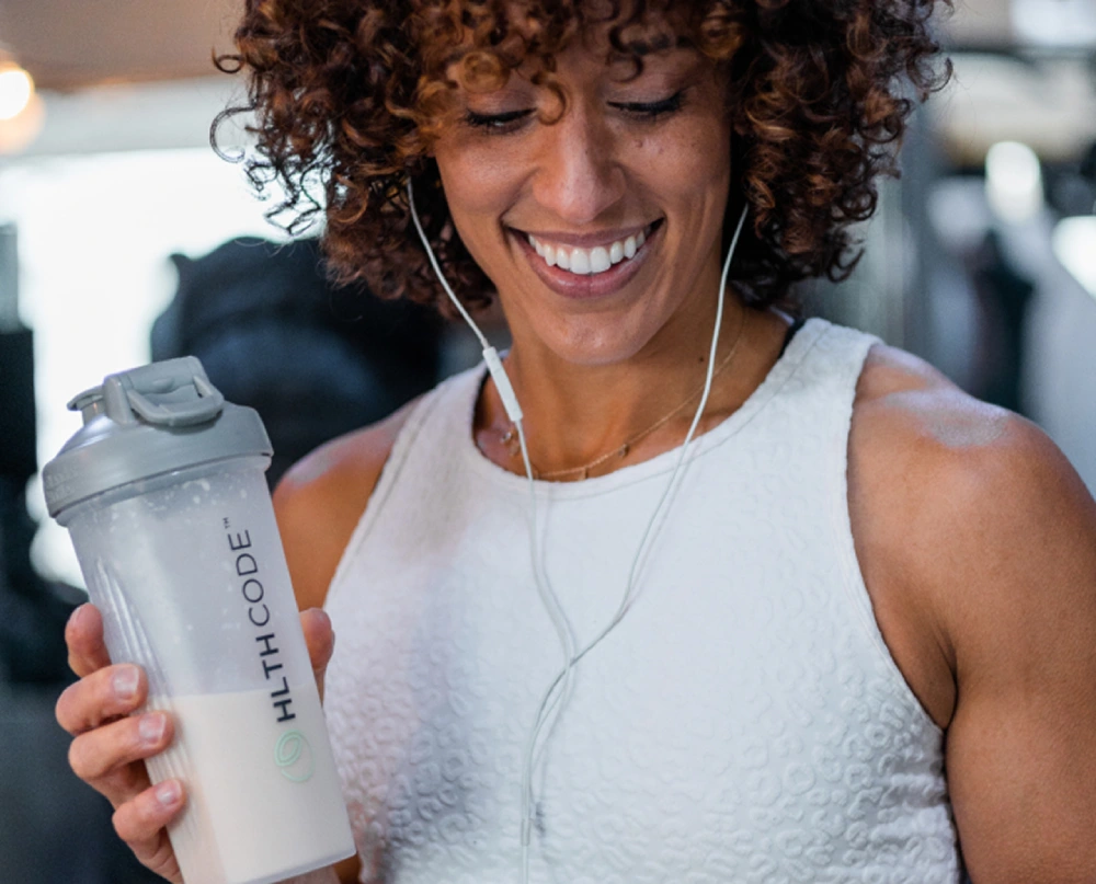 Person holding an HLTH Code shaker bottle, lifestyle photography from the HLTH Code website