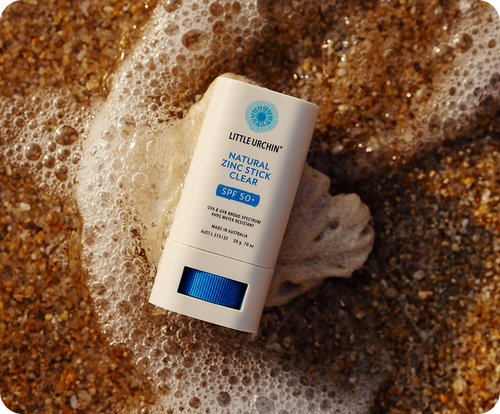 Little Urchin natural zinc sunscreen stick resting on wet sand, from the Little Urchin website