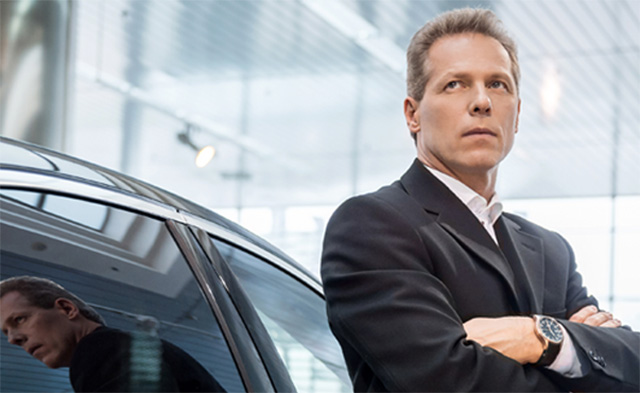 A Dryver professional driver standing beside a car