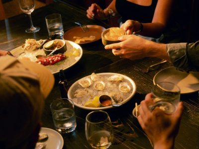 Friends sharing oysters, crudo and drinks around a candlelit restaurant table