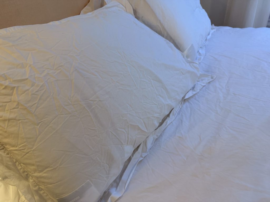 Prossioni white percale shams on two pillows, with the duvet cover beside them